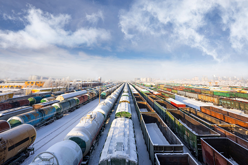 Many trains and freight cars at marshalling yard in winter on sunny day with blue sky and white clouds. Big train station. Urban landscape in big city. Wallpaper. Wide angle. Topside view