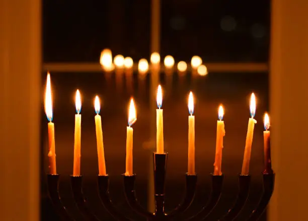 Chanukah Menorah candles burning glowing in front of window a dark at night