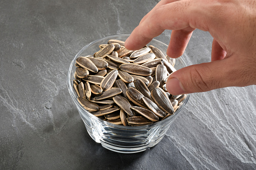 Eating sunflower seeds, hand taking sunflower seeds from a bowl