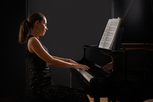 Musical instrument grand piano with woman performer.
