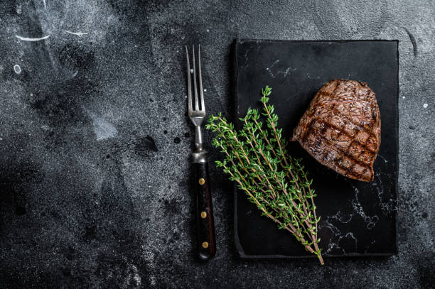 istock Grilled Rump steak with spices, cooked beef meat. Black background. Top view. Copy space 1437973393
