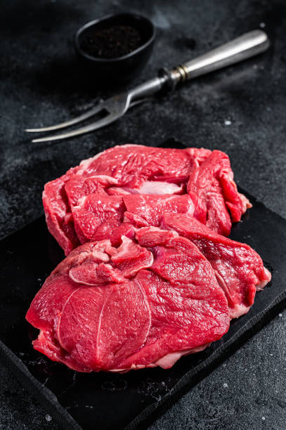 istock Raw Mutton fillet steaks from leg, uncooked lamb meat. Black background. Top view 1437973968