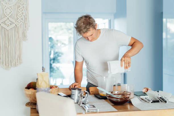 istock Young man cooking brownie cake on the light modern kitchen at home. Preparing steps for baking cake. Culinary hobby. Cooking online video classes on smartphone. Selective focus. copy space. 1437974173