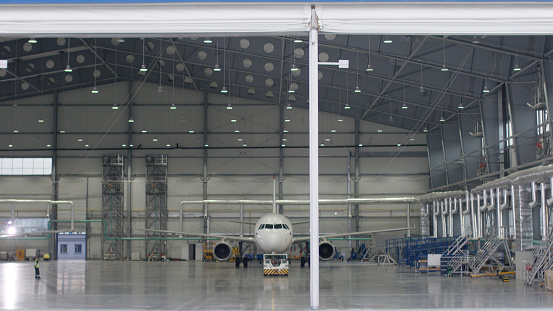 Two private jets waiting for maintenance in a repair hangar of an airport.