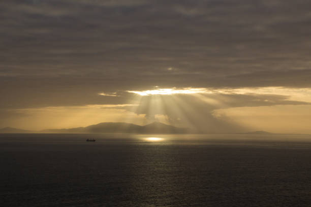 istock Sunbeams Meeting the sea with freighter 1437977581