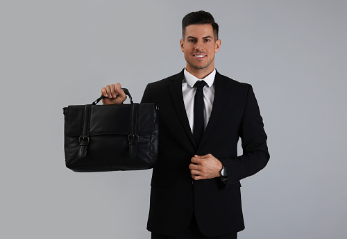 Businessman with stylish leather briefcase on light grey background