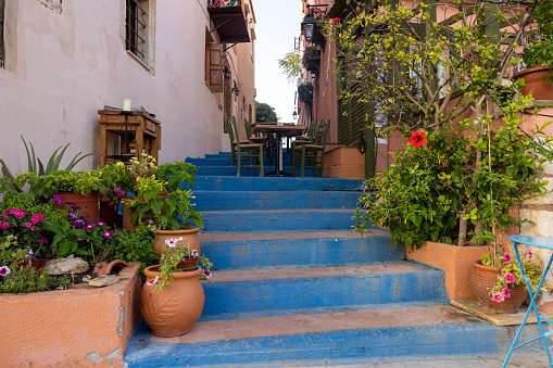 Rethymnon, Crete, Greece - Sept 18, 2021: Small narrow street with blue stairs in Old Town of Rethymnon, Crete island, Greece