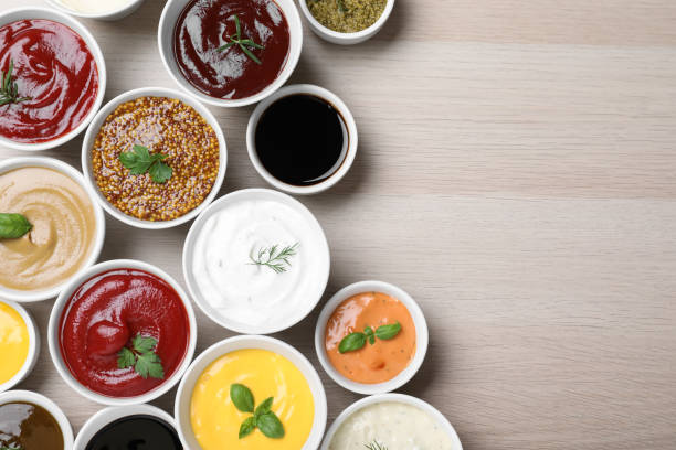 istock Many different sauces and herbs on wooden table, flat lay. Space for text 1437981300