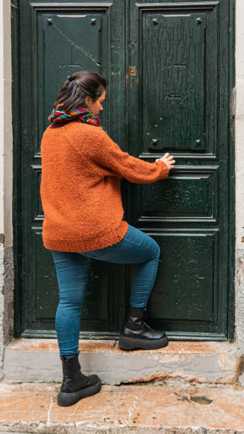 Woman opening an old wooden door stock photo