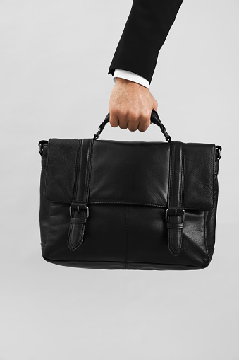 Man holding stylish leather briefcase on light grey background, closeup