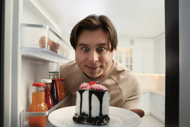 istock Happy overweight man taking cake out of refrigerator in kitchen, view from inside 1437983838