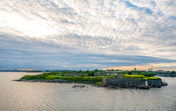 Suomenlinna island and lighthouse - leaving by ferry from Helsinki and pink sunset and yellow flowers of some flowers on the island - very decorative at dusk