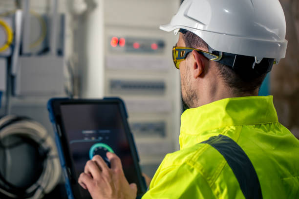 istock Man an electrical technician working in a switchboard with fuses, uses a tablet. 1437984422