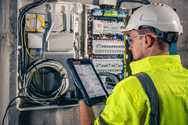 istock Man, an electrical technician working in a switchboard with fuses, uses a tablet. 1437984441