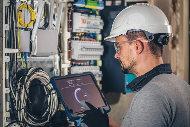 istock Man, an electrical technician working in a switchboard with fuses, uses a tablet. 1437984448