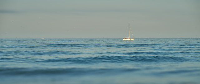 sailboat on blue sea with horizon on background