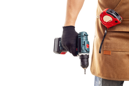 Man in apron and gloves holding cordless screwdriver isolated on white background. Men work, home renovation, construction or carpentry business.