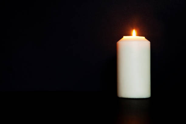 white burning candle on black background. burns in darkness, copy space. eternal memory, mourning, white burning candle on black background. burns in darkness, copy space. eternal memory, mourning, moment of silence, day of remembrance, of loss moment of silence stock pictures, royalty-free photos & images