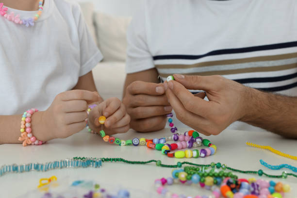 istock Father with his daughter making beaded jewelry at table, closeup 1437985947