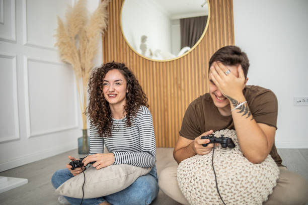 istock Young couple playing video games on console at home, having a good time 1437986782