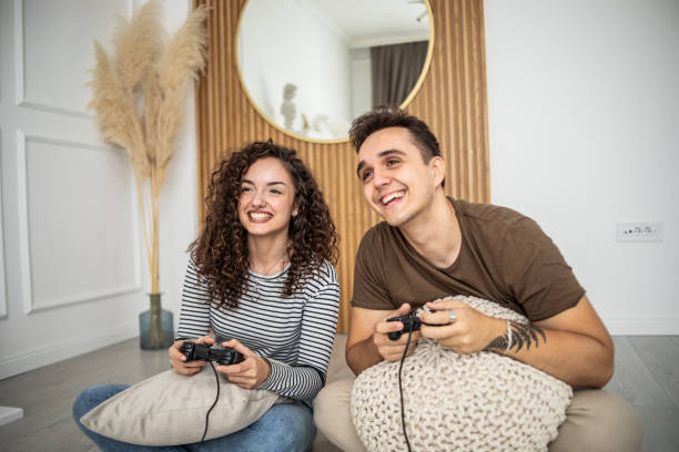 istock Young couple playing video games on console at home, having a good time 1437986790