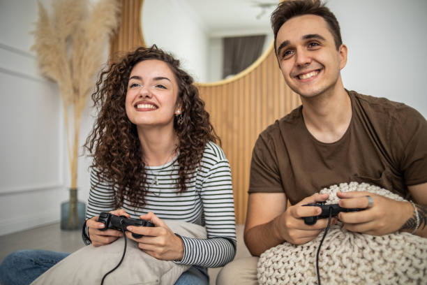 istock Young couple playing video games on console at home, having a good time 1437986814