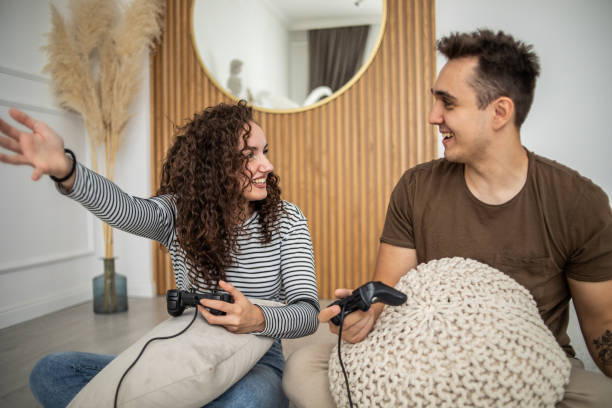 istock Young couple playing video games on console at home, having a good time 1437986836