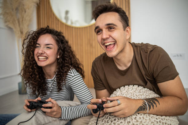 istock Young couple playing video games on console at home, having a good time 1437986849