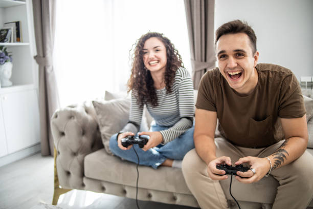 istock Young couple playing video games on console at home, having a good time 1437986885