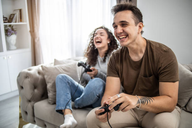 istock Young couple playing video games on console at home, having a good time 1437986892