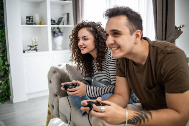 istock Young couple playing video games on console at home, having a good time 1437986894