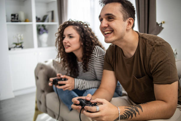 istock Young couple playing video games on console at home, having a good time 1437986895