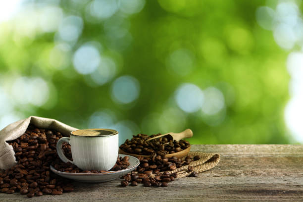 istock Cup of aromatic hot coffee and beans on wooden table outdoors. Space for text 1437987715