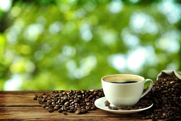 istock Cup of aromatic hot coffee and beans on wooden table outdoors. Space for text 1437987716