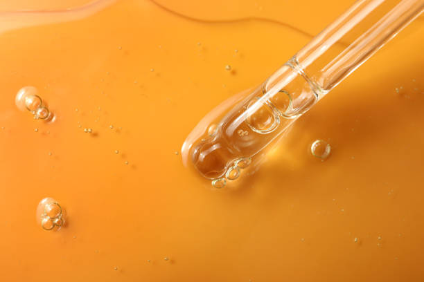 istock Dripping hydrophilic oil from pipette on orange background, closeup 1437988718