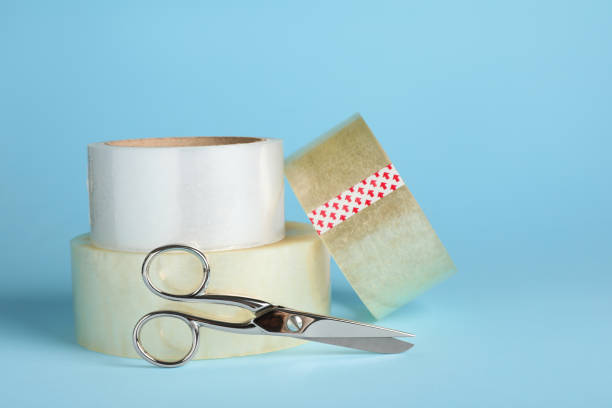istock Rolls of adhesive tape and scissors on light blue background. Space for text 1437989655