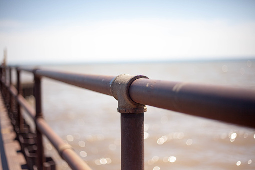 The rusty railing on a pier with Lake Ontario in the Background.