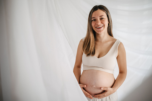 One woman, portrait of a beautiful pregnant woman touching her belly.