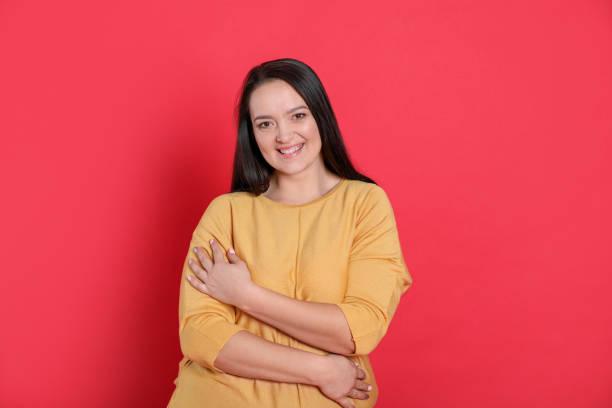 istock Beautiful overweight woman with charming smile on red background 1437993420