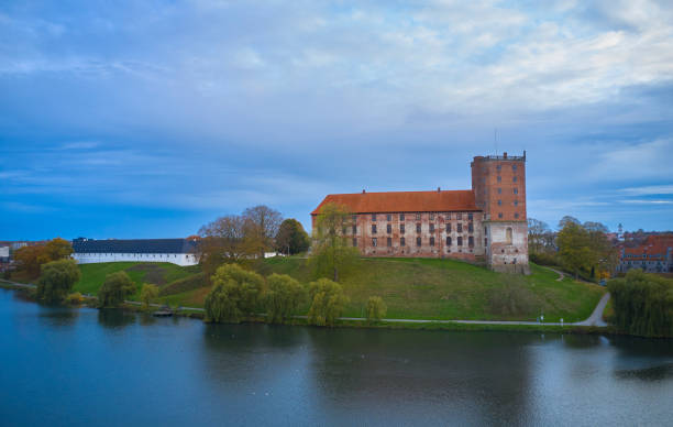 Hillerod, Denmark - April 21, 2025: Beautiful spring blooms frame a majestic Danish Frederiksborg castle by a tranquil river. Hillerød, Denmark.