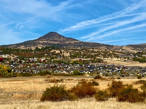 Panoramic view of the countryside in the Rogue Valley with a hill and a neighborhood on a bright fall day.