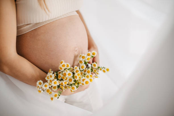 istock Pregnant beauty holding flowers 1437994630