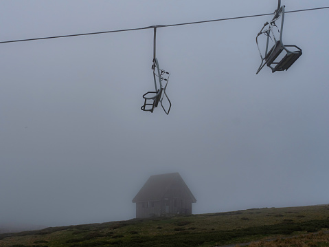 Empty chairs hang from a ski lift next to a little hut at Mount Buller