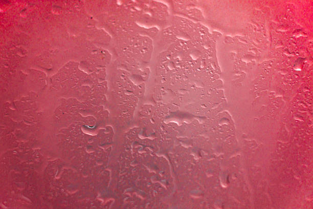 drops of rainwater running down red glass