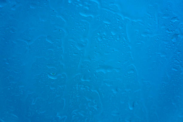 drops of rainwater running down the  blue glass