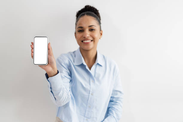 istock Young woman showing a mobile phone with white screen. Focus on foreground. 1437998487