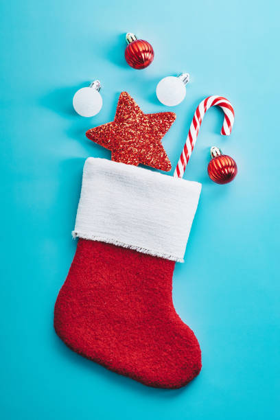 istock Red stocking with Christmas decorations and candy cane on blue background 1437999640