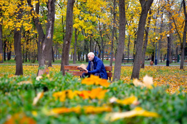 istock young man reading a book outdoors sitting on a bench in autumn park 1438000089