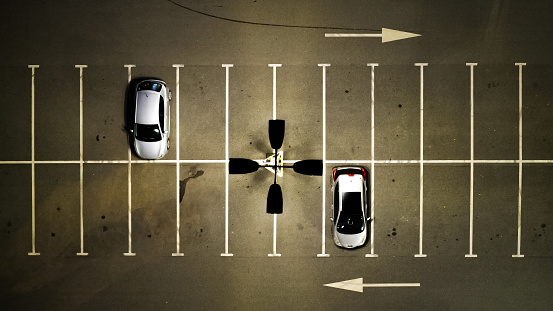 Top view at night on the parking lot with two cars, left arrow, right arrow. Lots of empty parking spaces.