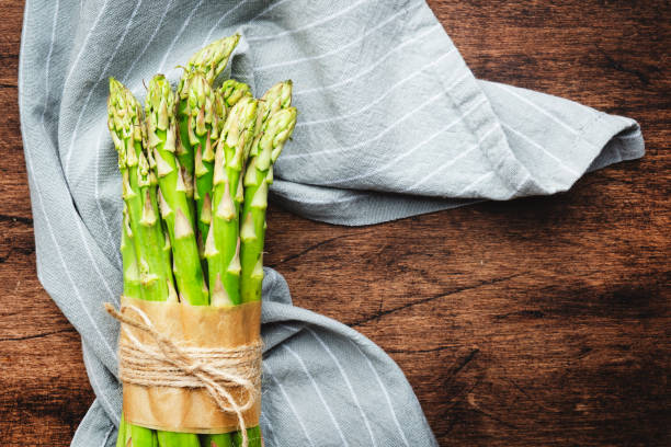 istock Fresh asparagus bunch on rustic wooden kitchen table background, top view, copy space 1438003075